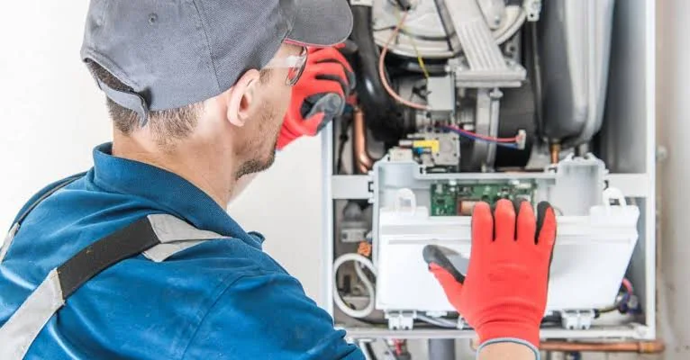 Technician servicing the control components of a residential furnace